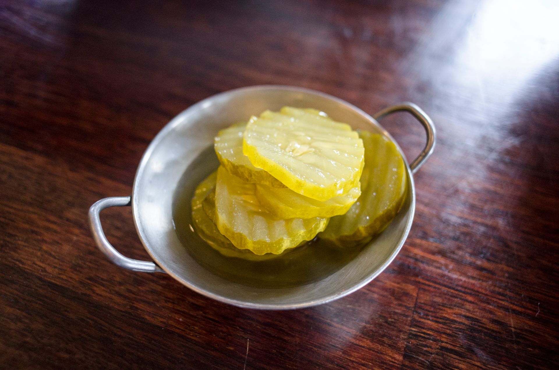 Sliced yellow pickles in a small metal bowl