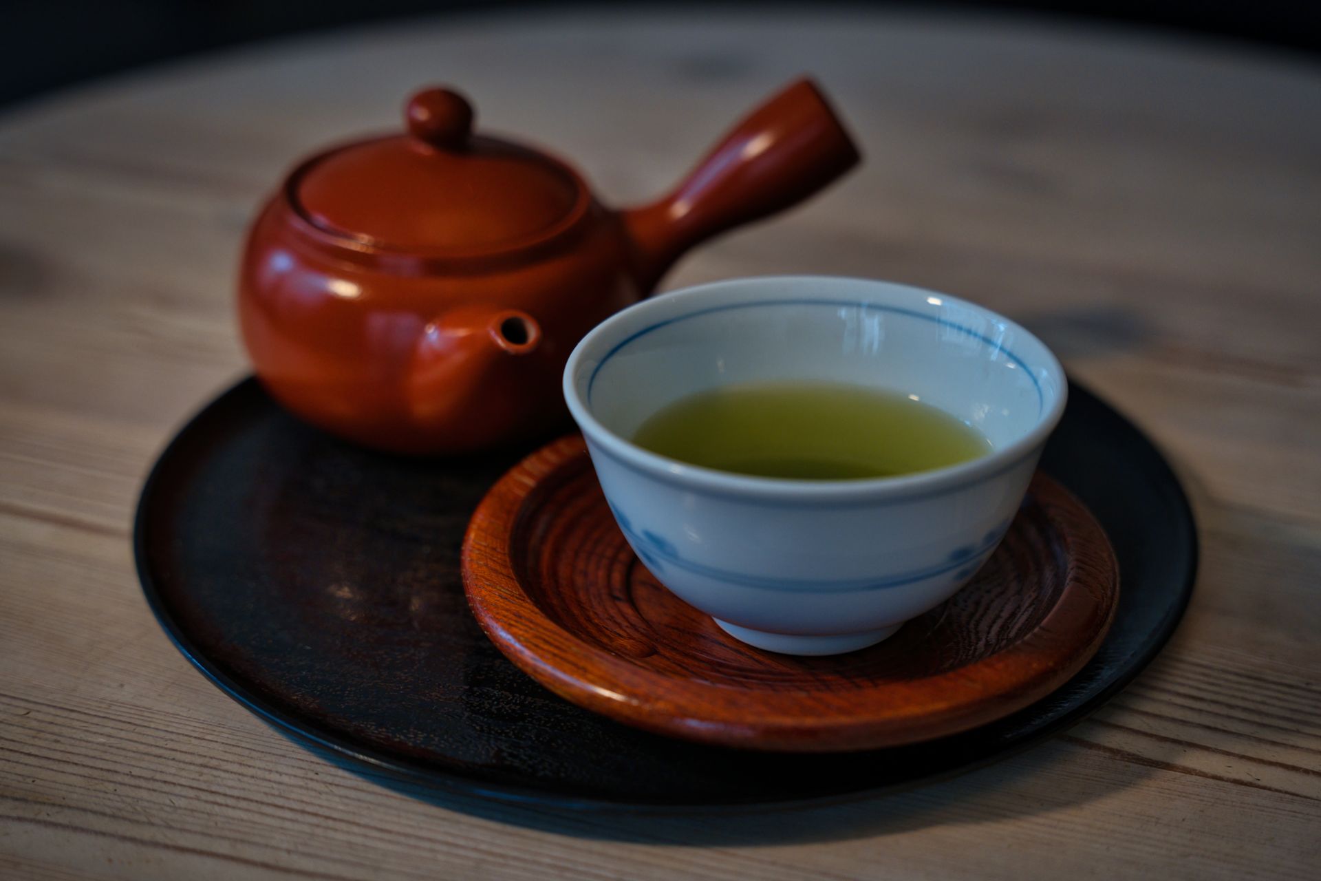 Green tea in a cup with a clay teapot