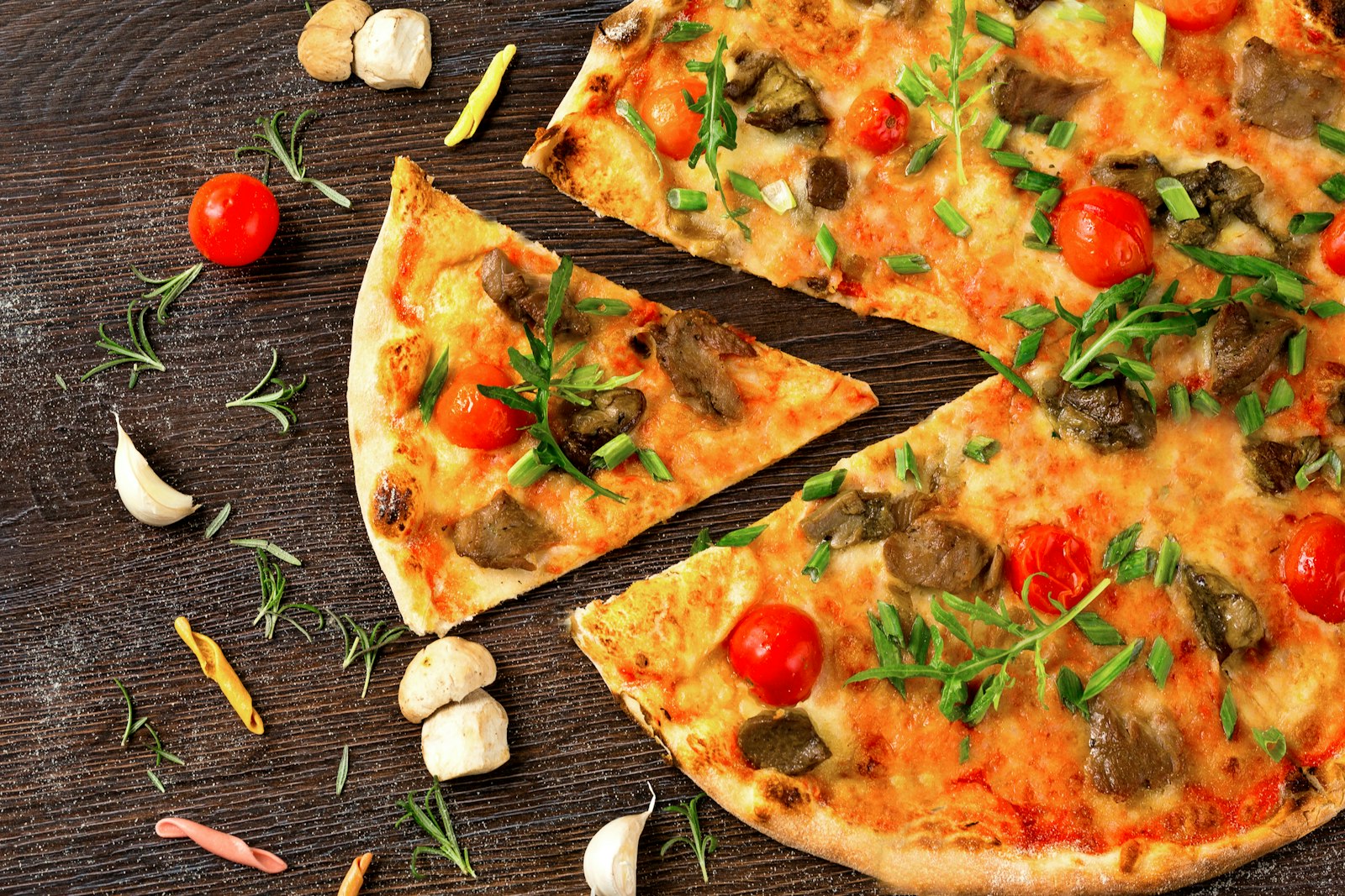 Thin crust pizza with tomatoes and arugula, sliced into wedges