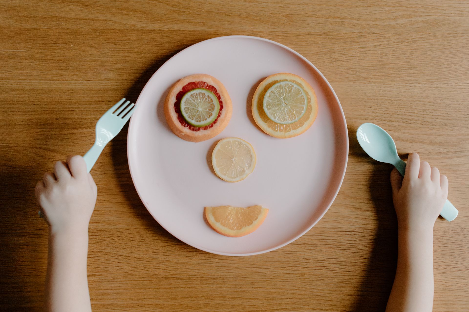 A smiling face made of citrus slices on a pink plate