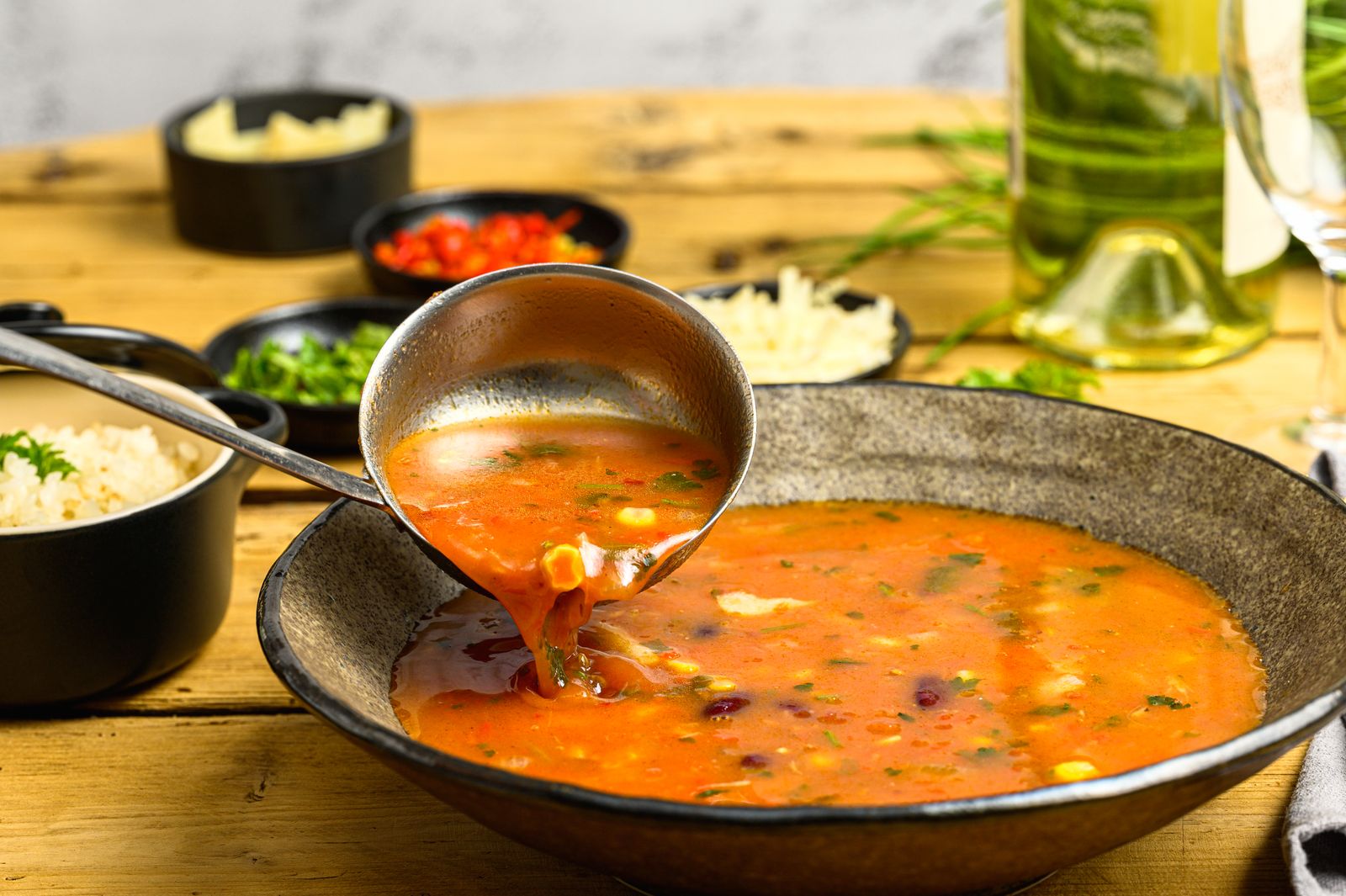 A ladle pouring vegetable soup into a rustic bowl