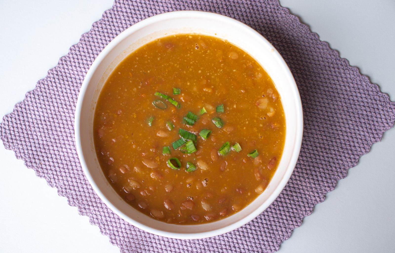 Homemade navy bean soup with green onions in a white bowl