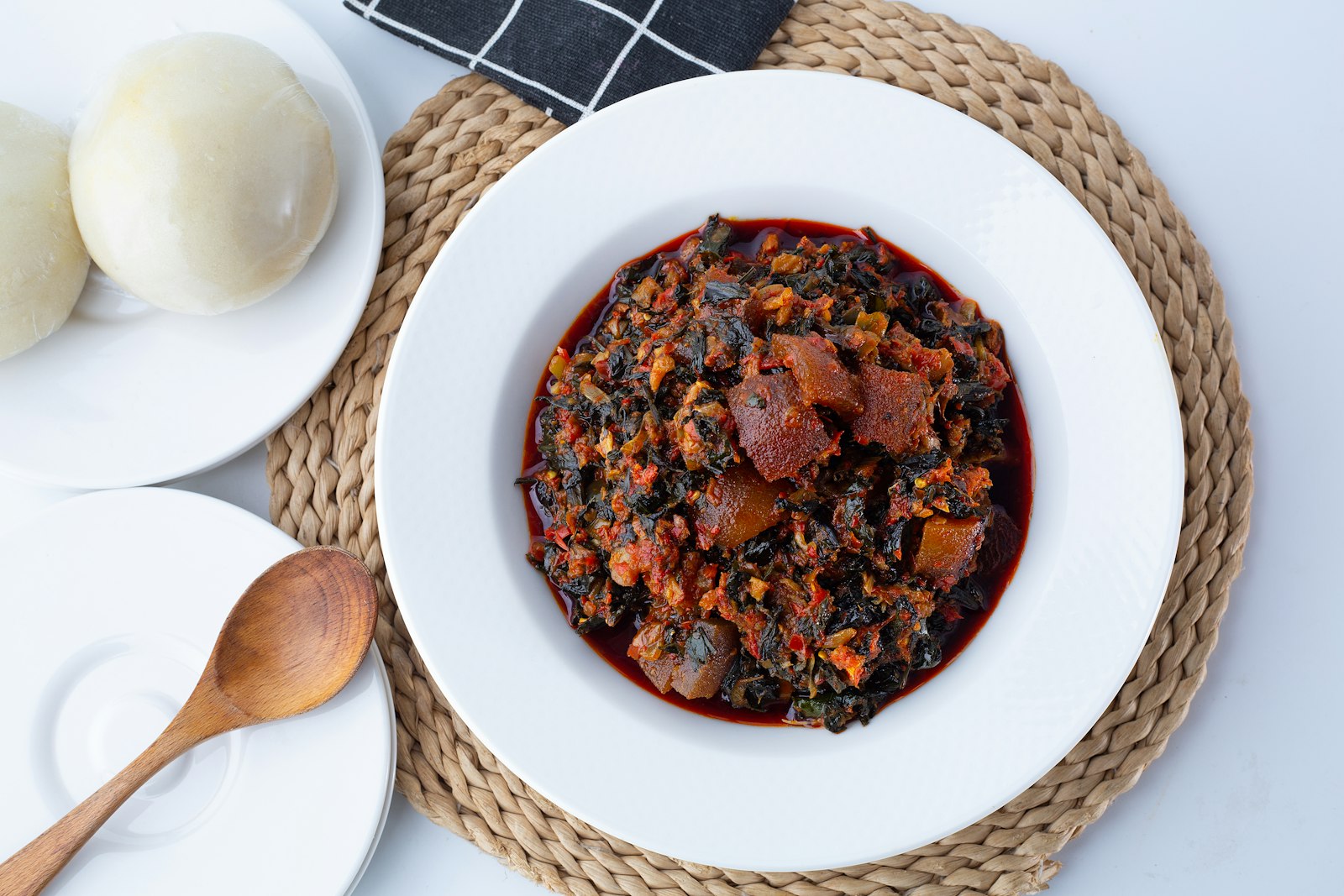 A rich red stew with smoked sausage in a white bowl