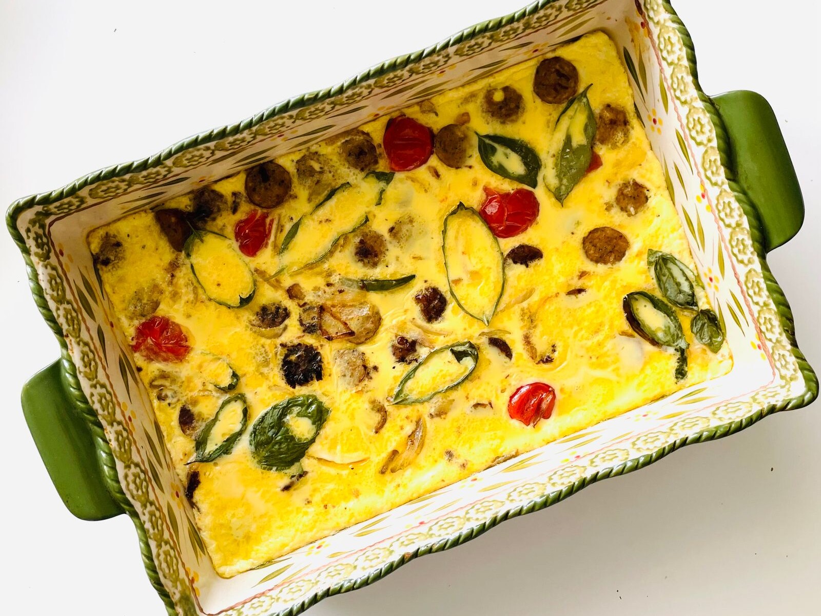 An egg breakfast casserole with vegetables and cheese in a baking dish