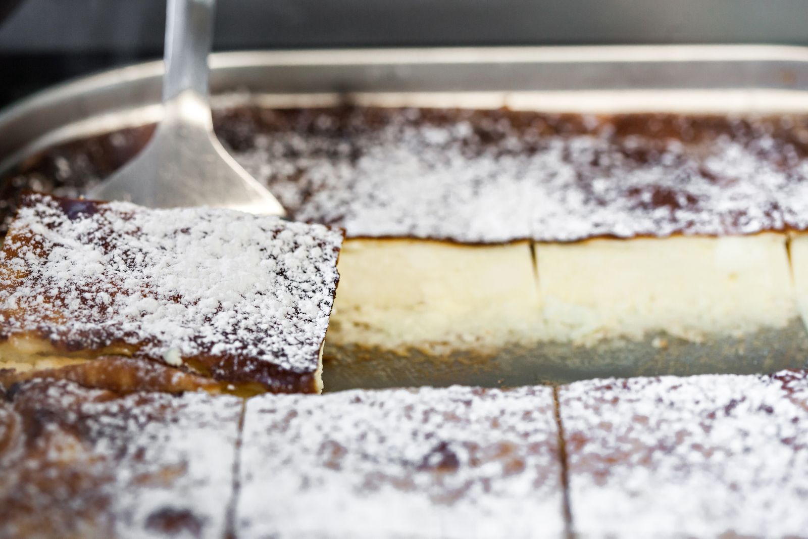 Sopapilla cheesecake bars dusted with sugar in a baking pan