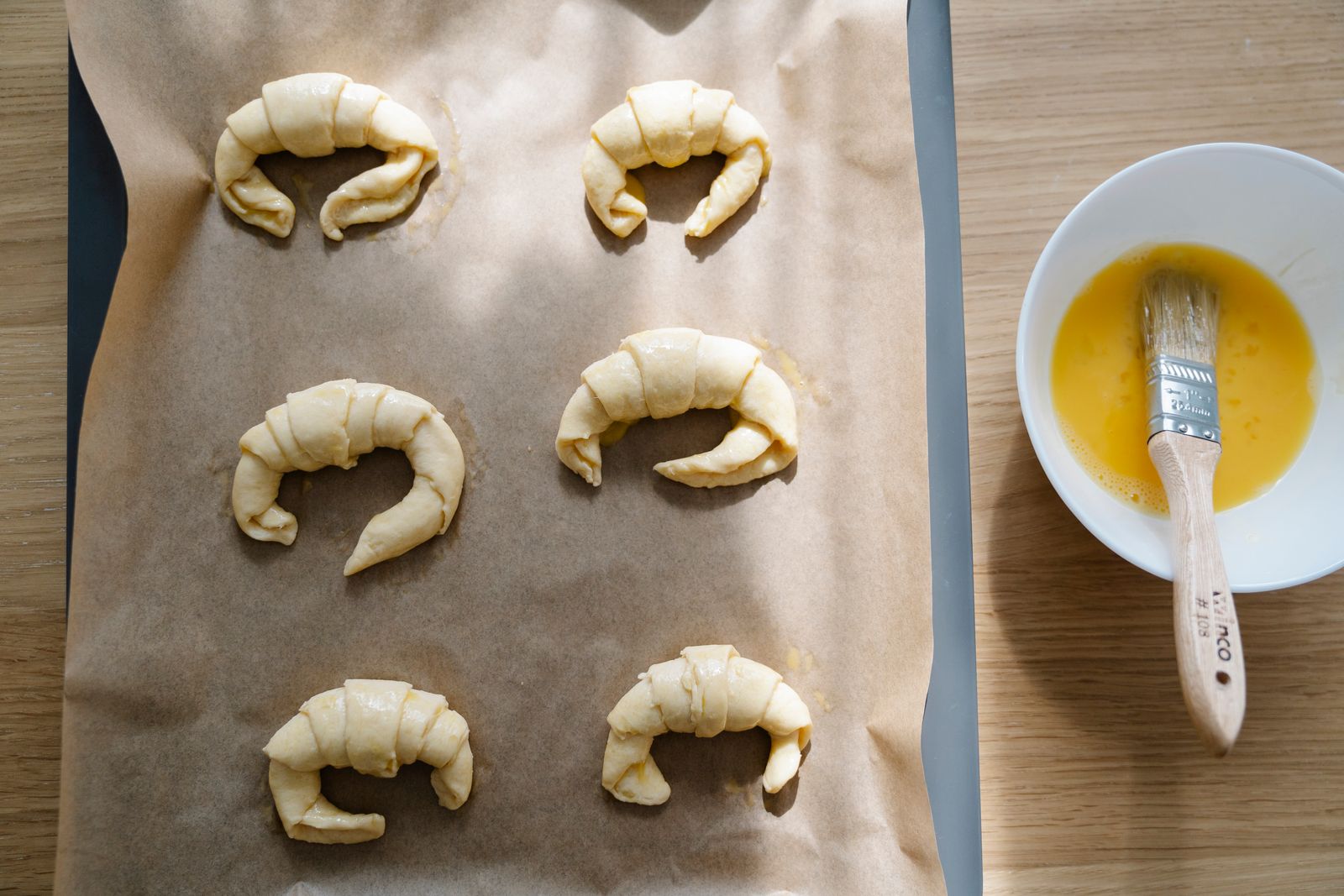Shaped crescent roll dough brushed with egg wash on parchment