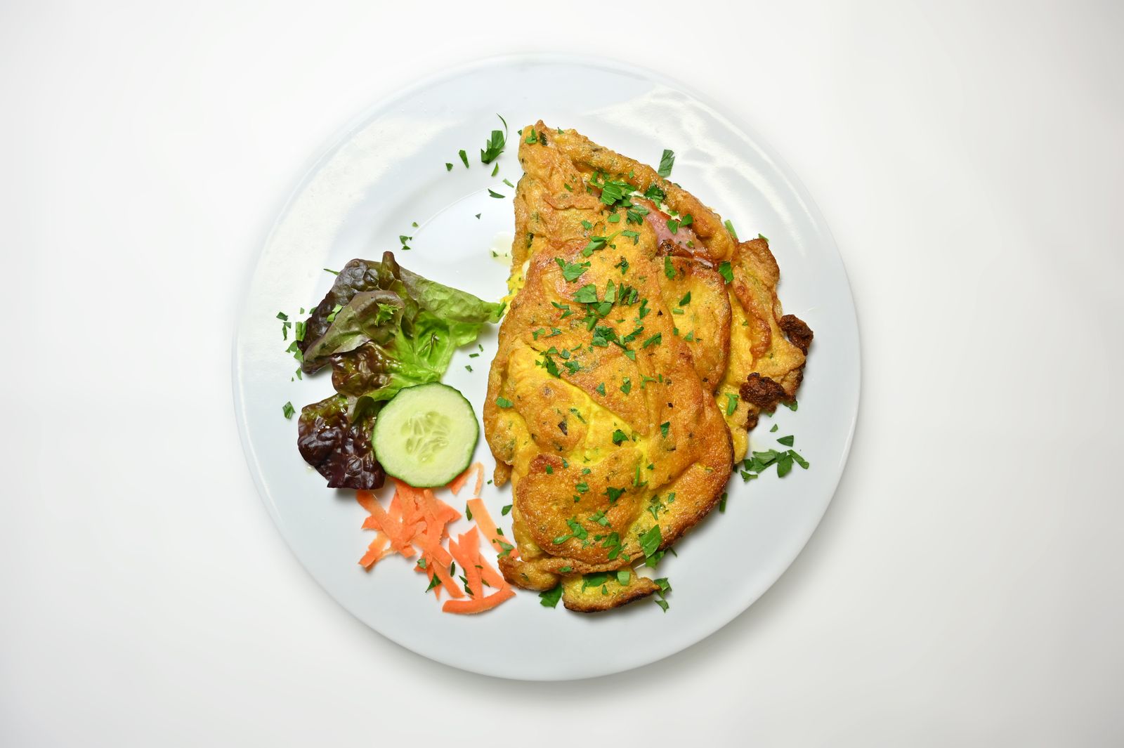 A folded omelette with fresh salad on a white plate