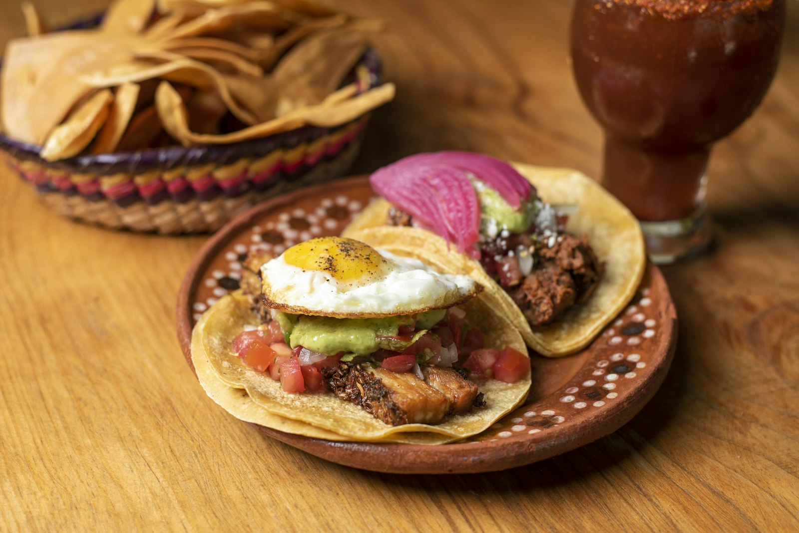 Breakfast tacos topped with fried eggs on a wooden table