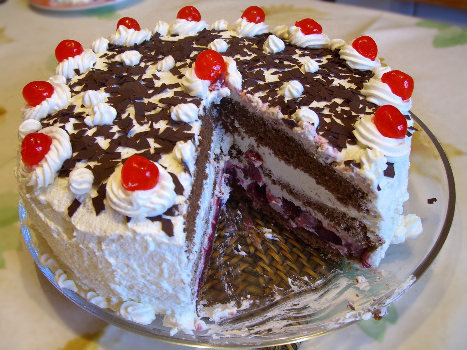 Black Forest cake with whipped cream, chocolate shavings and cherries, one slice cut out