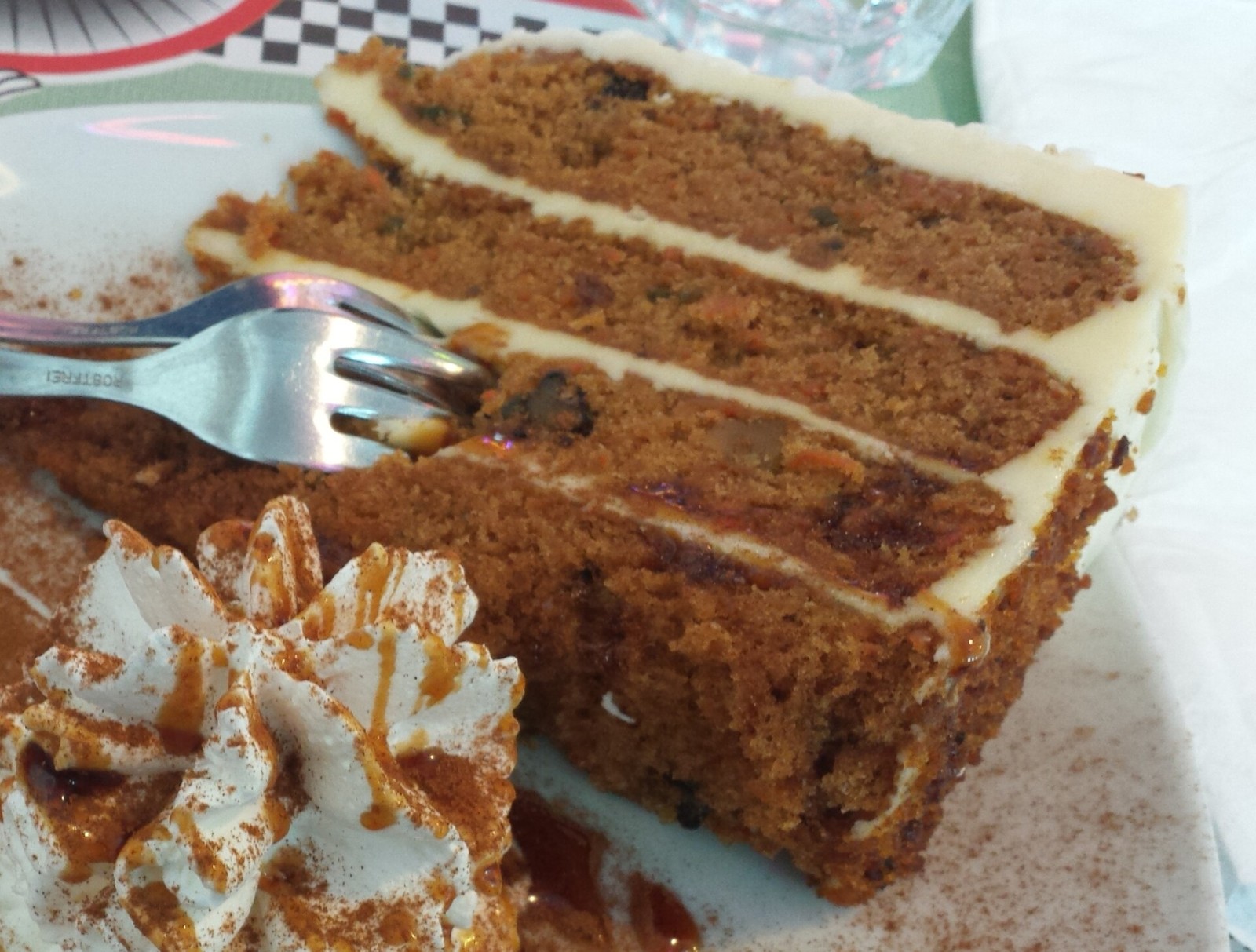 Slice of layered carrot cake with cream cheese frosting on a plate