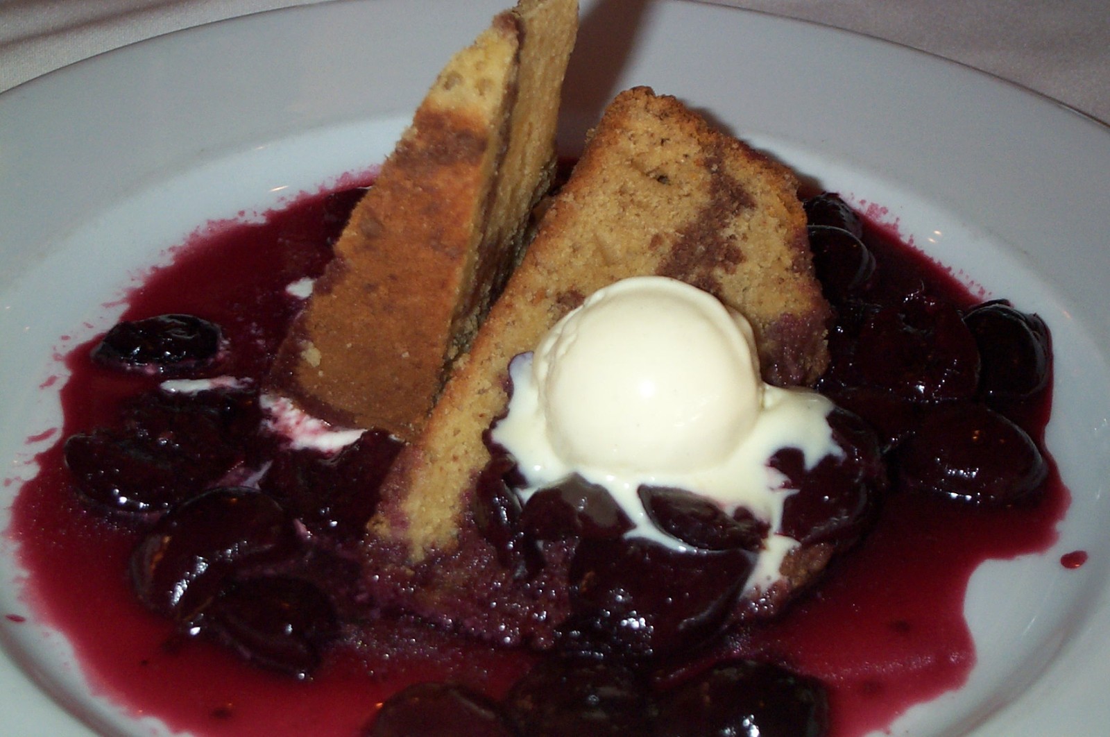 Warm dark cherry sauce over vanilla ice cream with slices of pound cake