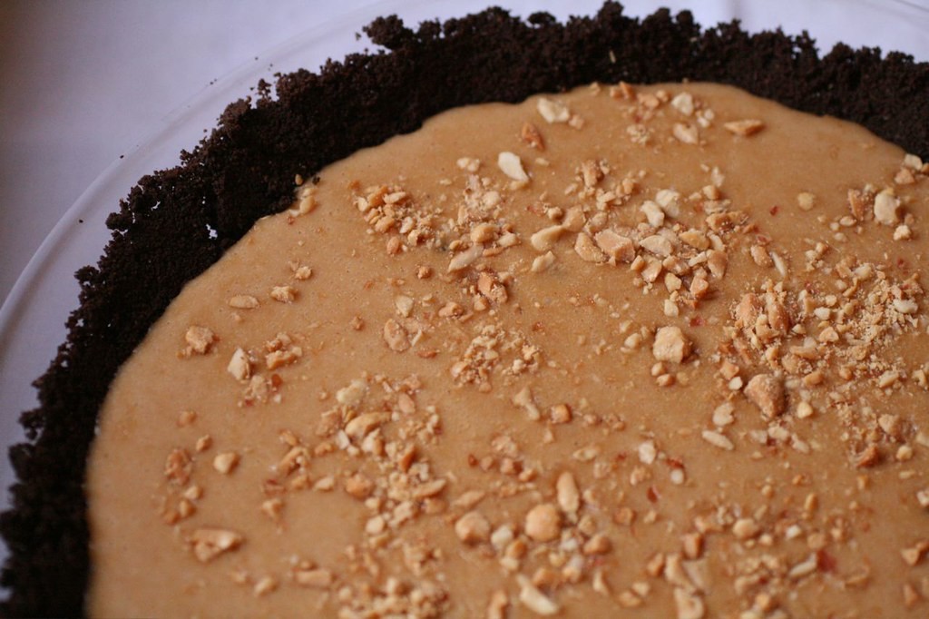Peanut butter pie in a chocolate cookie crust topped with chopped peanuts