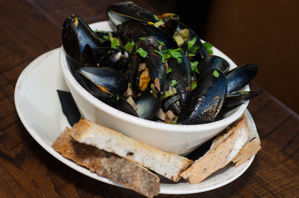 Bowl of steamed mussels in garlic broth with grilled bread