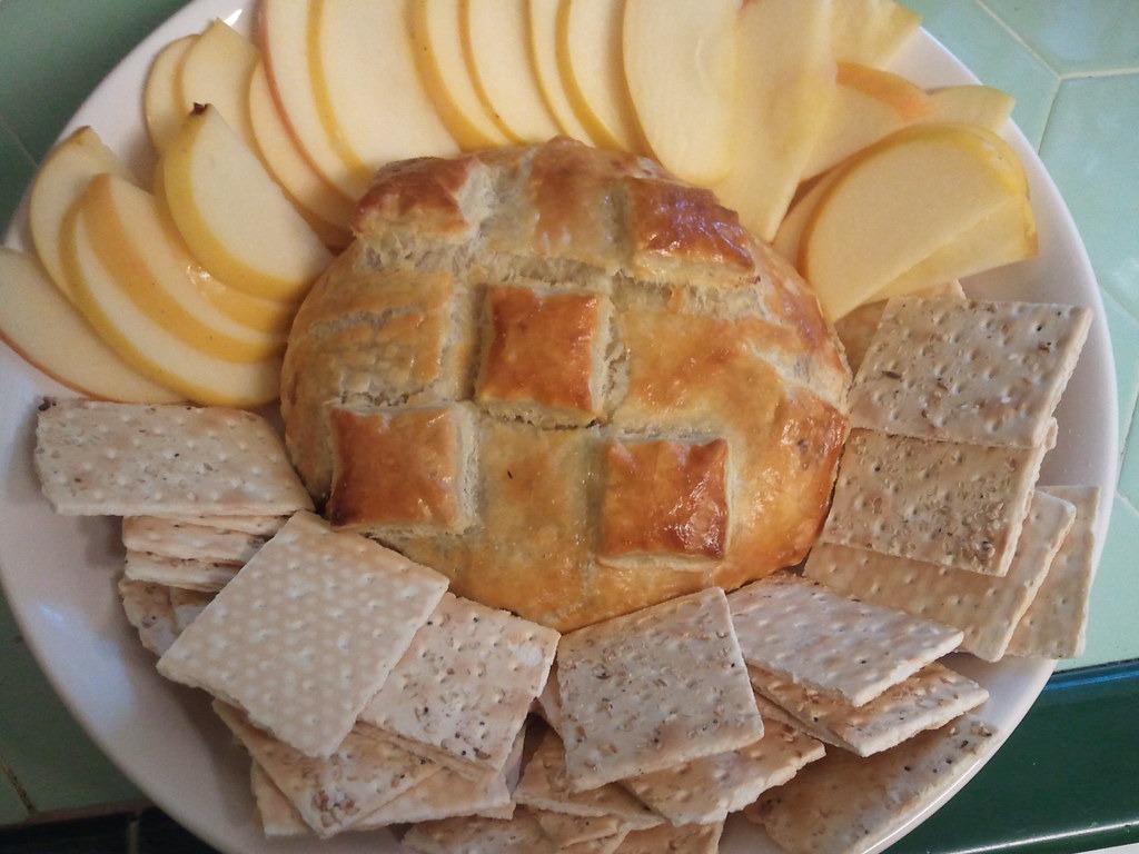 Brie baked inside a crosshatched bread loaf with crackers