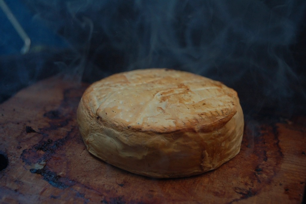 Whole baked camembert cheese on a wooden board