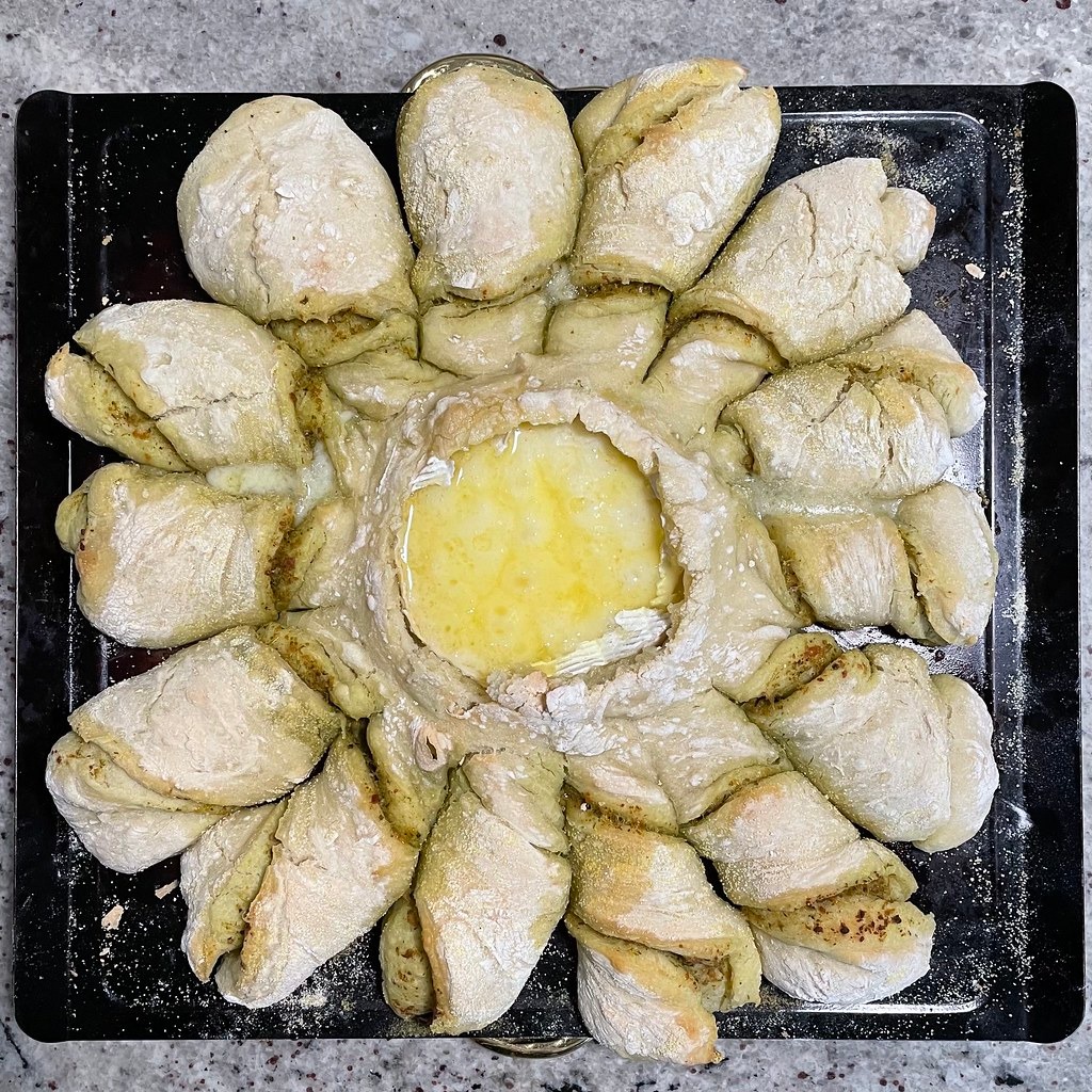 Pesto stuffed brie pull-apart pastry ring on a baking tray