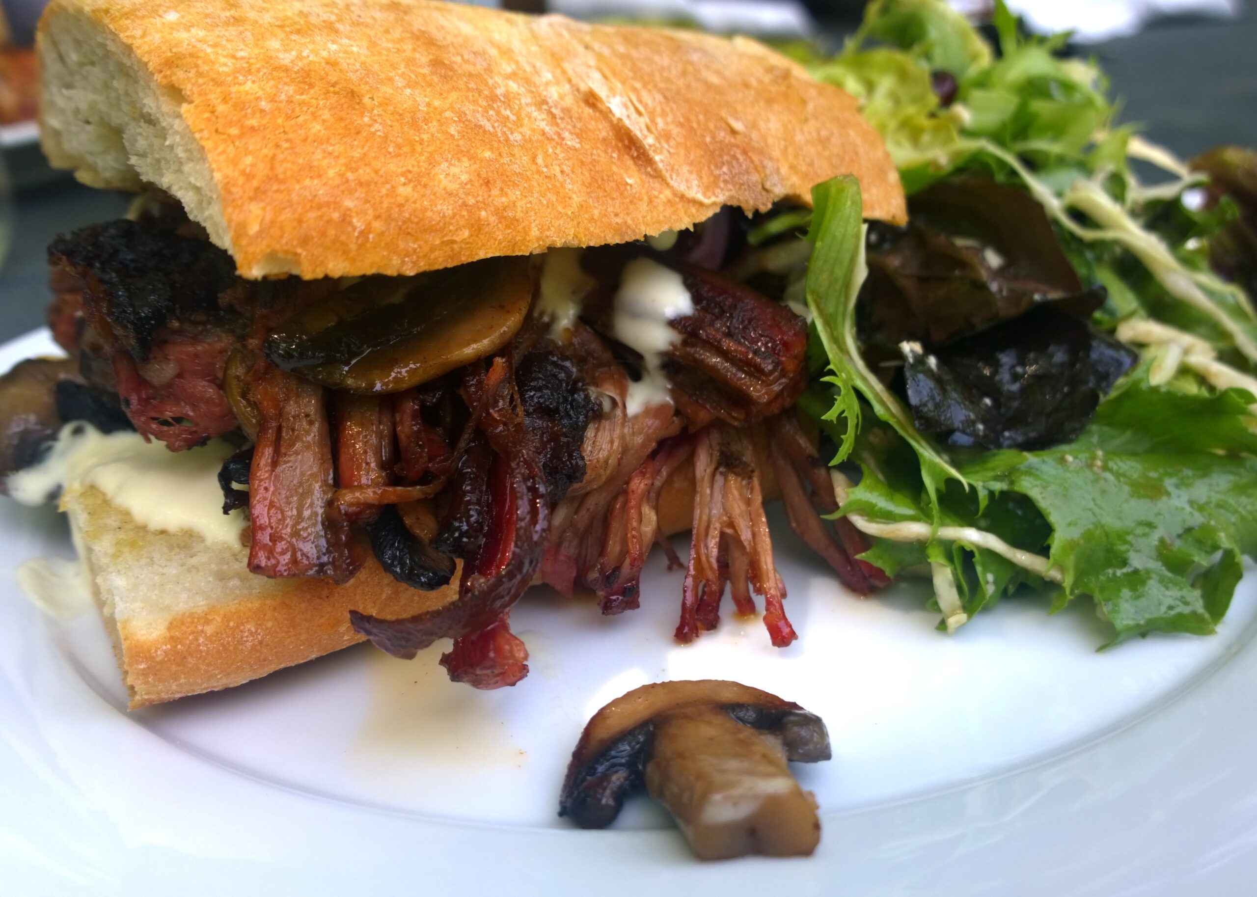 Barbecue beef sandwich on a crusty roll with greens