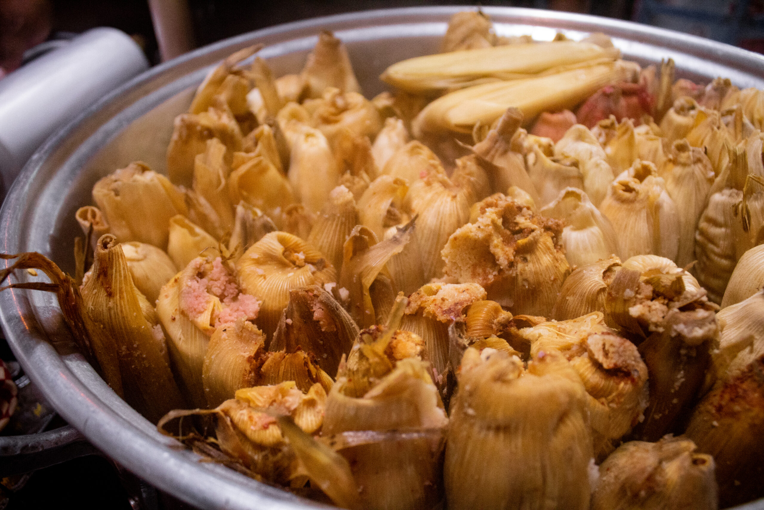A full pot of hot steamed tamal bundles in corn husks