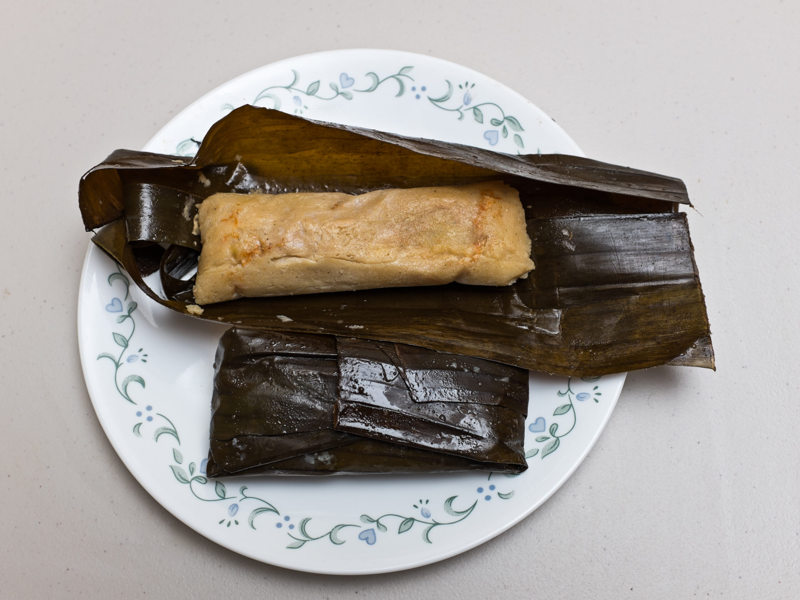 Salvadoran Christmas tamales in banana leaves on a white plate