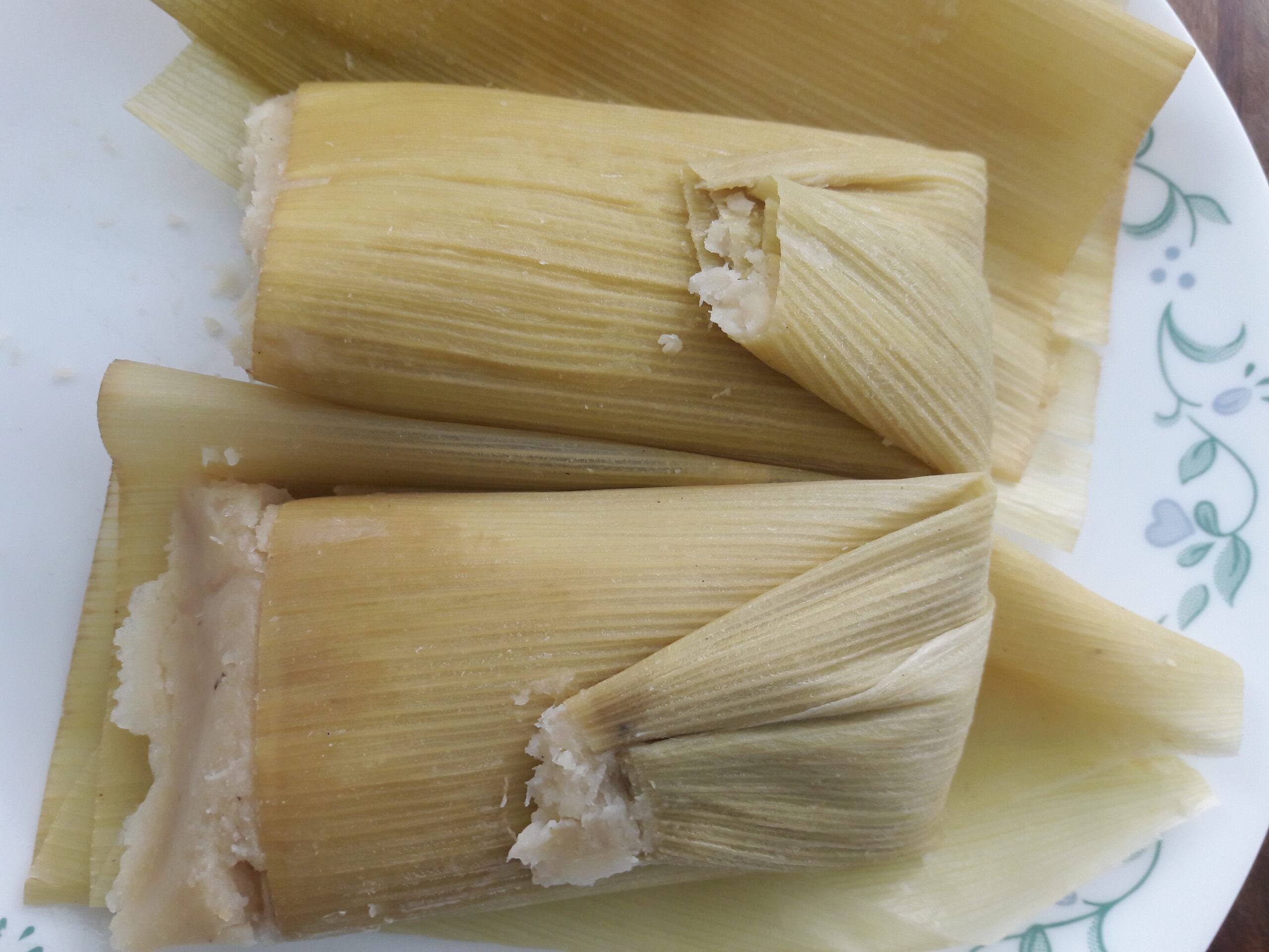 Sweet fresh corn uchepos in green husks on a plate