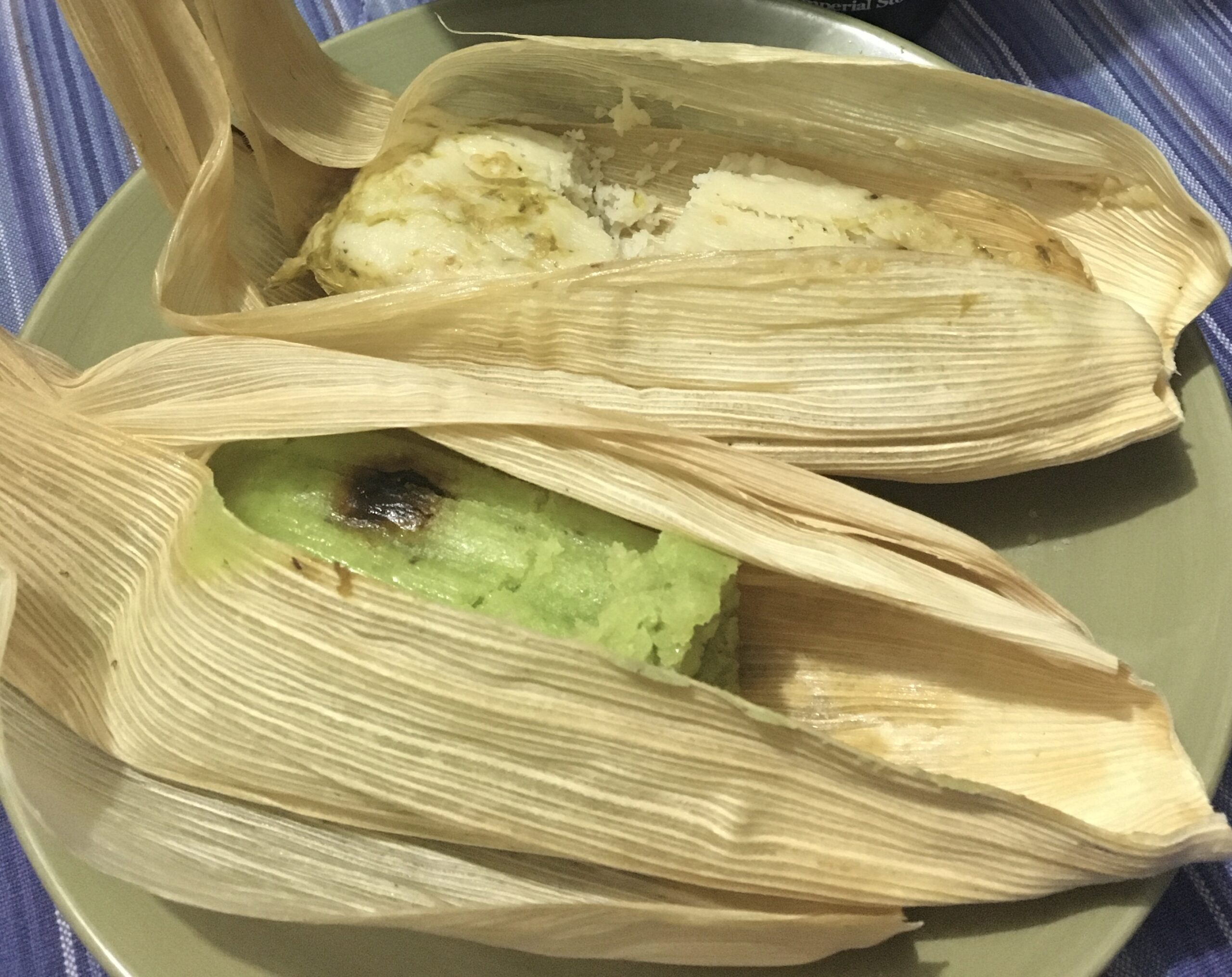 Savory green tamal opened in its corn husk next to a sweet green tamal