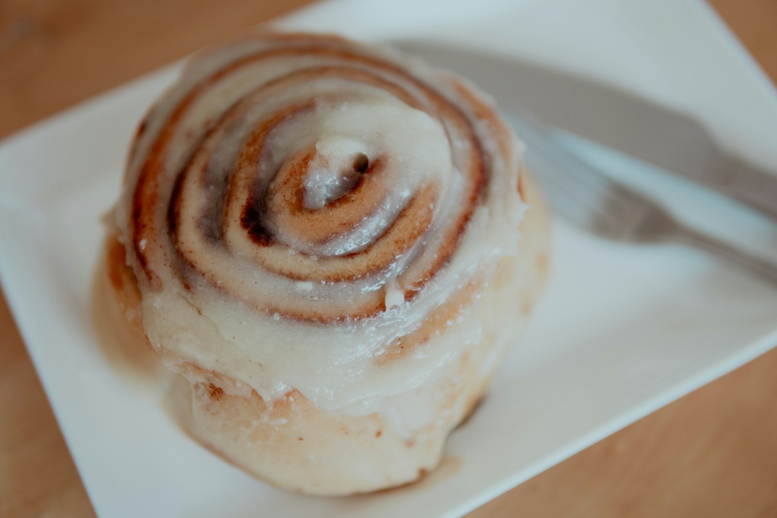 Glazed cinnamon roll on a white plate