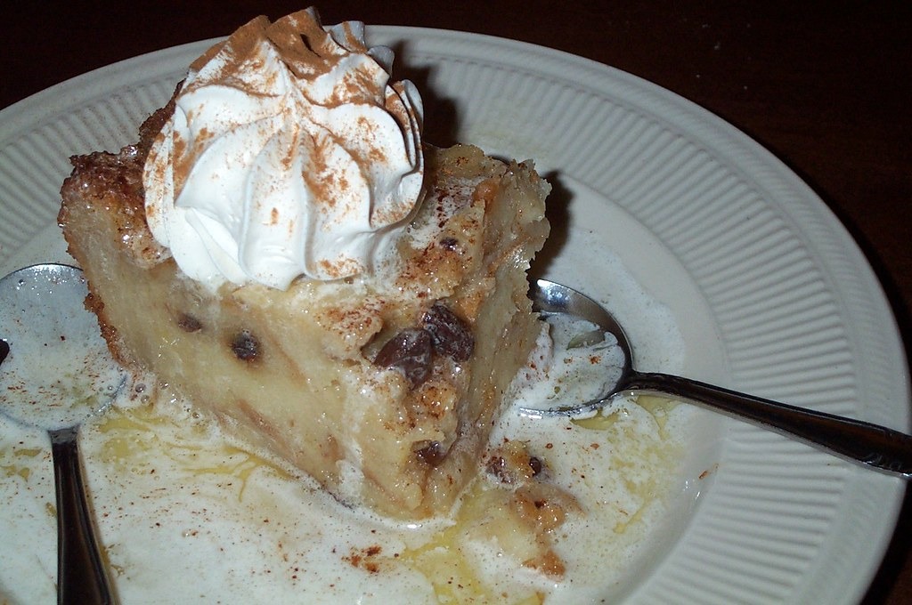 Warm bread pudding with whipped cream on a white plate