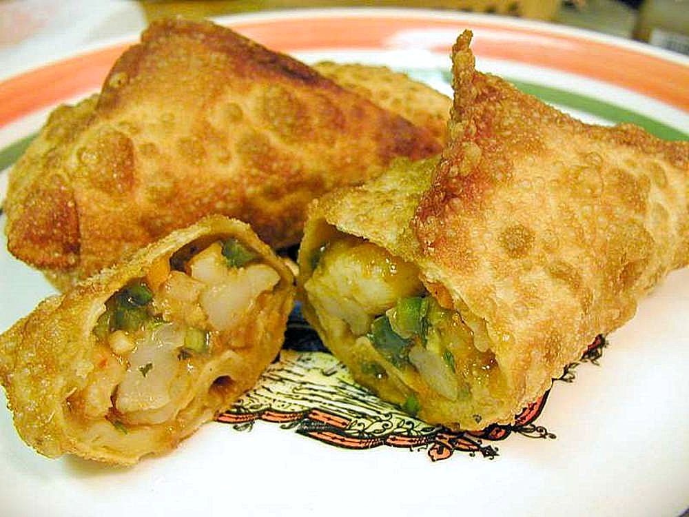Crispy golden egg rolls cut open on a plate with dipping sauce