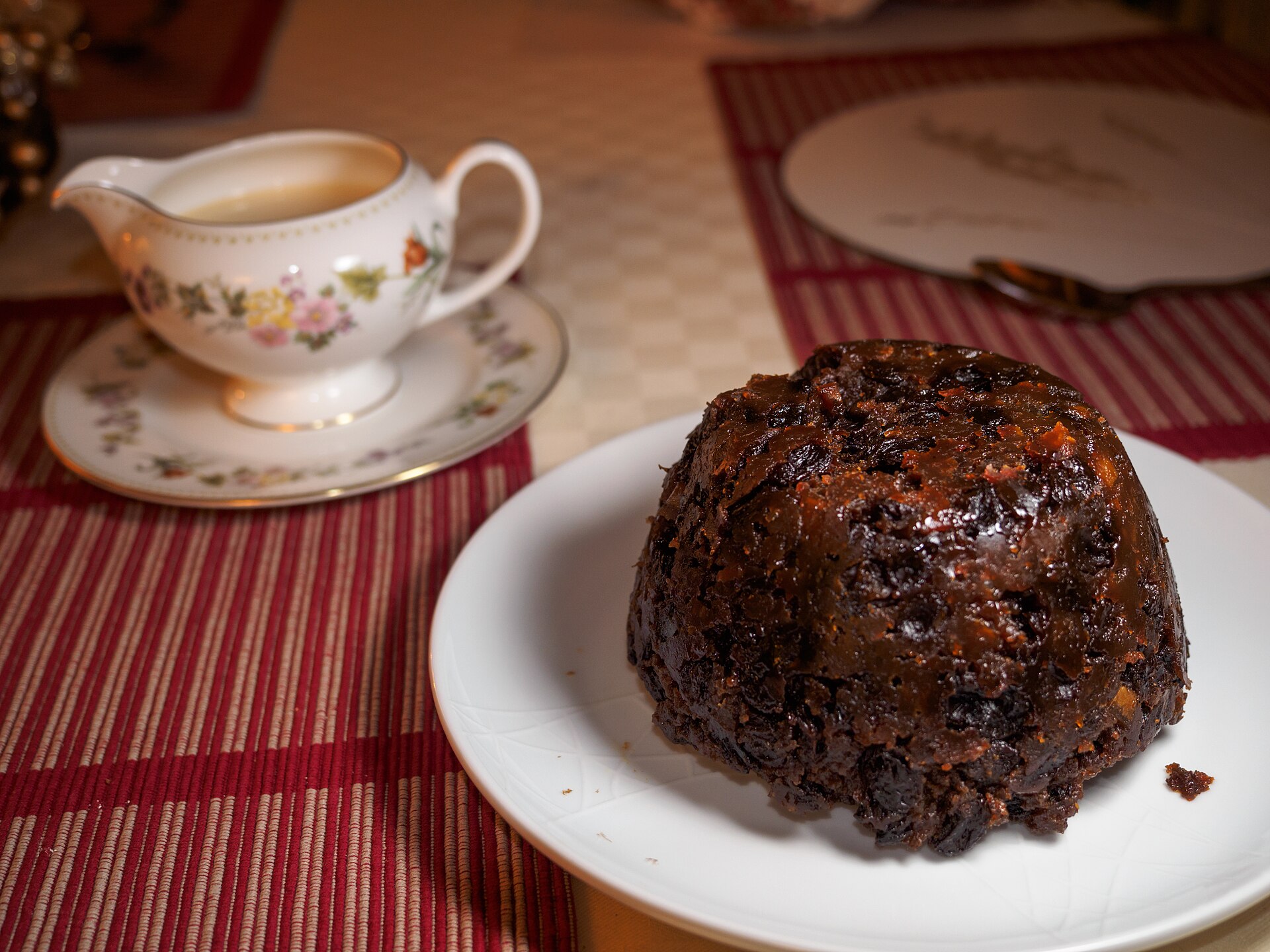 Dark steamed Christmas pudding on a white plate