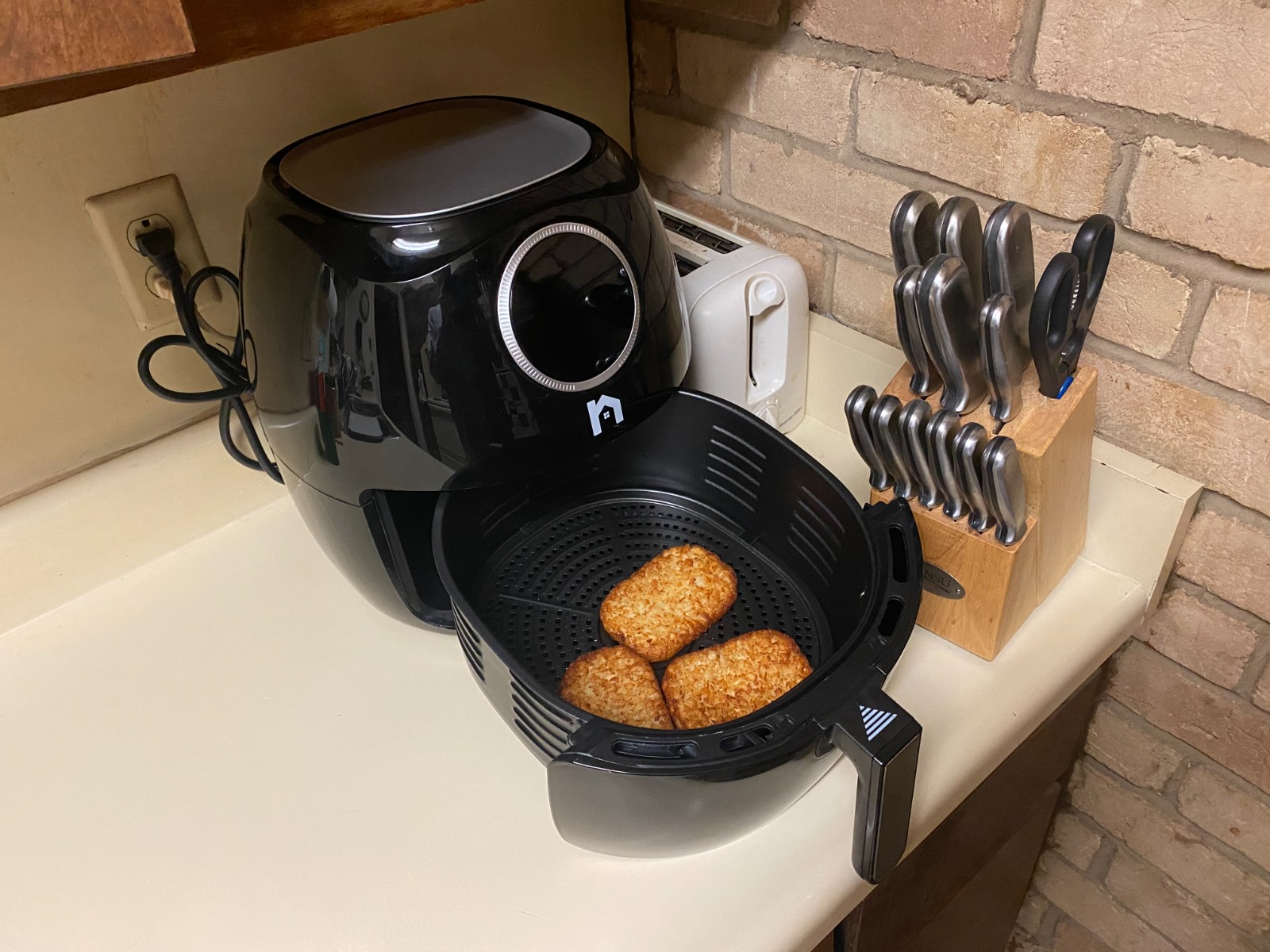 Air fryer basket holding hash brown patties on a kitchen counter