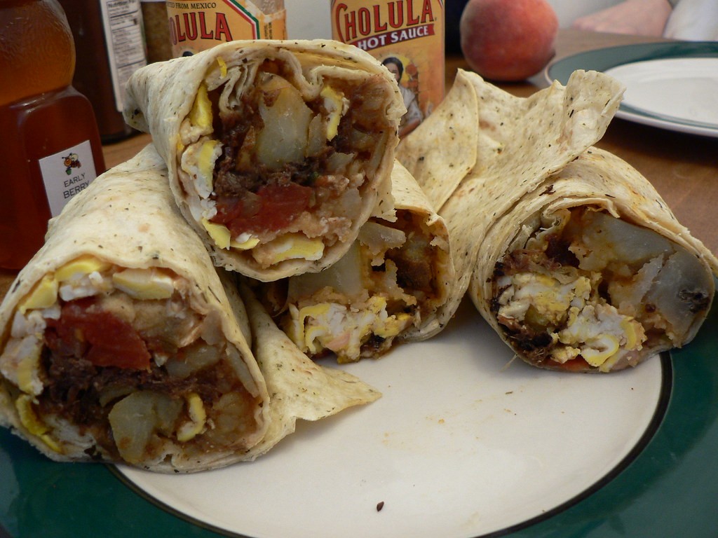 Breakfast burritos cut in half showing eggs, hash browns and sausage inside