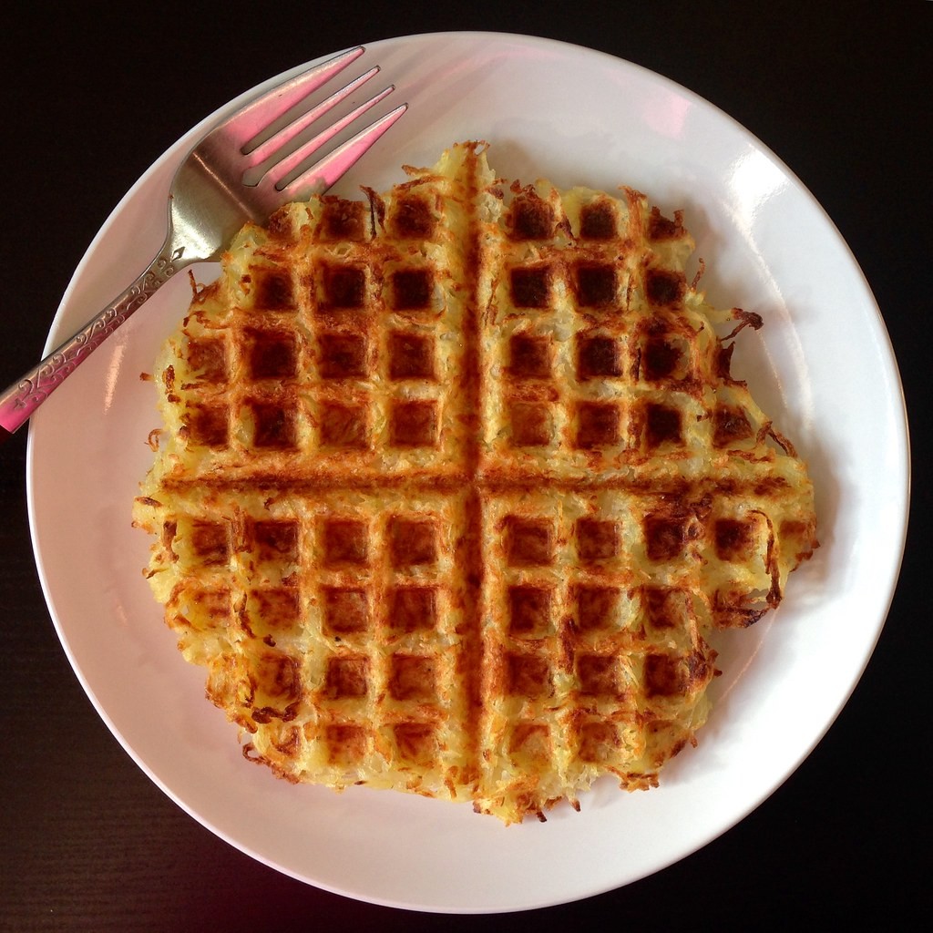 Crispy hash brown waffle on a white plate with a fork