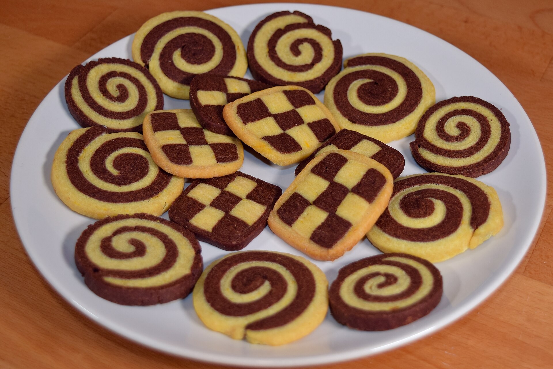 Chocolate and vanilla pinwheels and checker biscuits arranged on a white plate