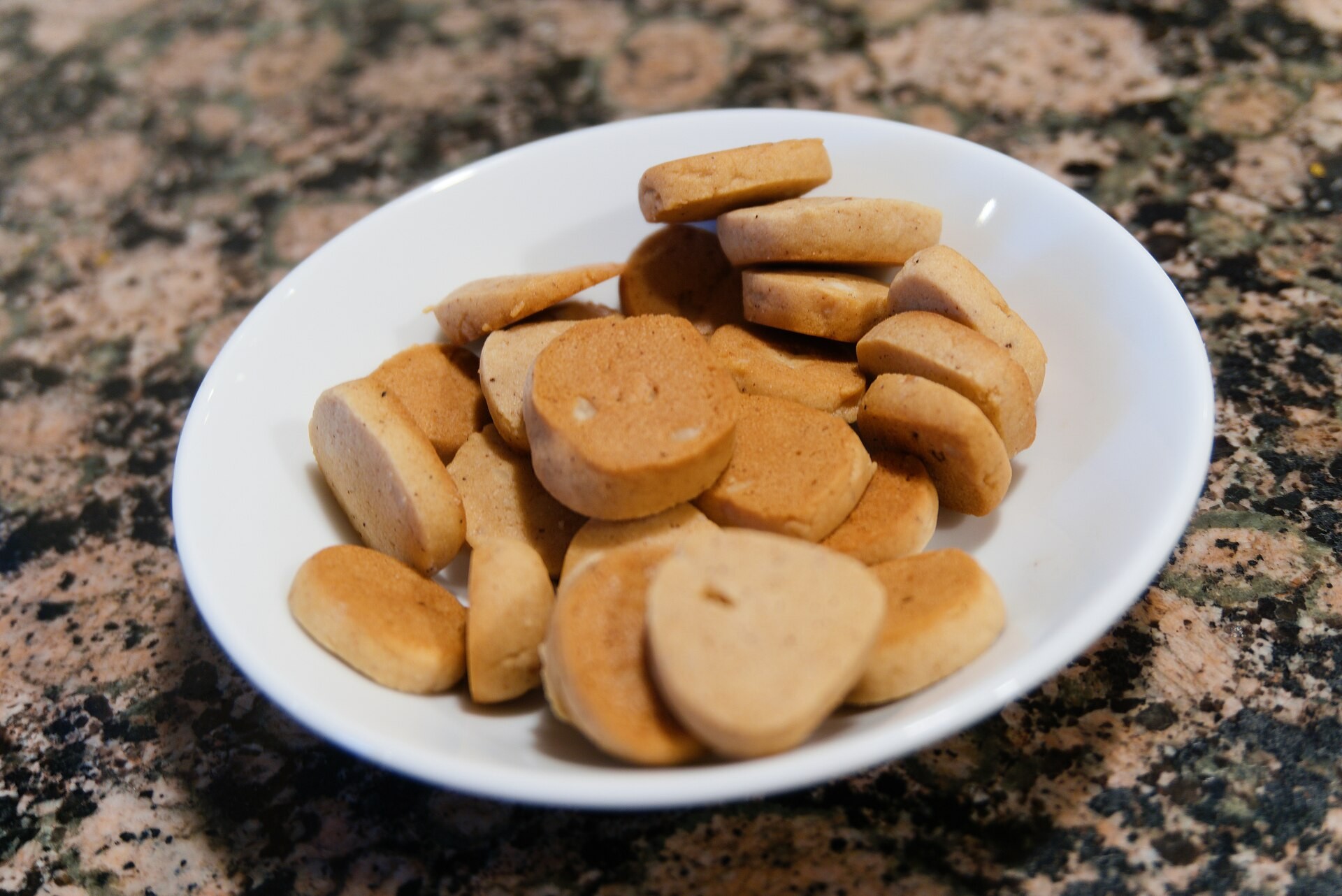A white bowl filled with small spiced peppernut biscuits