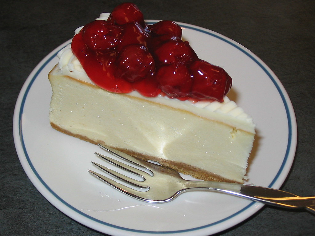 Cherry topped cheesecake slice on a white plate