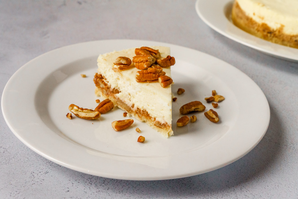 Pecan pie cheesecake slice topped with candied pecans