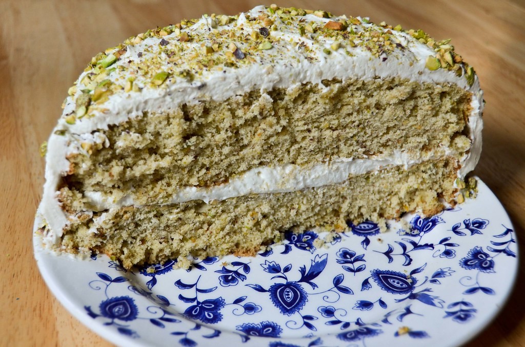 Slice of nut sponge layer cake with honey buttercream and chopped pistachios
