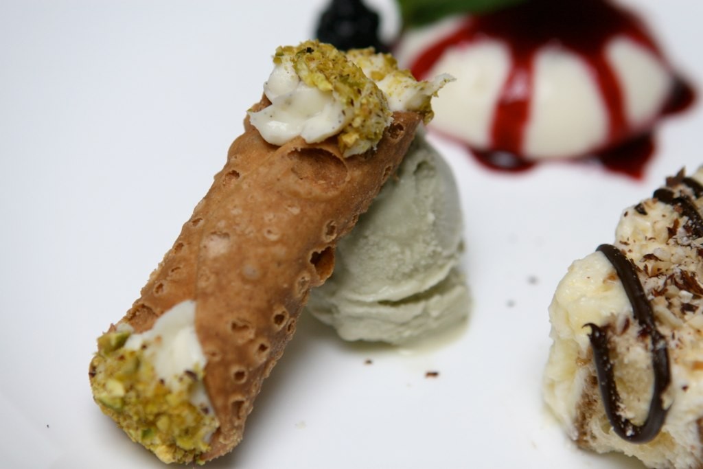 Crisp cannoli shell with ricotta filling and ends dipped in crushed pistachios