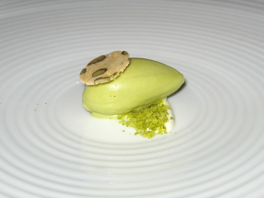 Scoop of pale green pistachio ice cream on a white plate