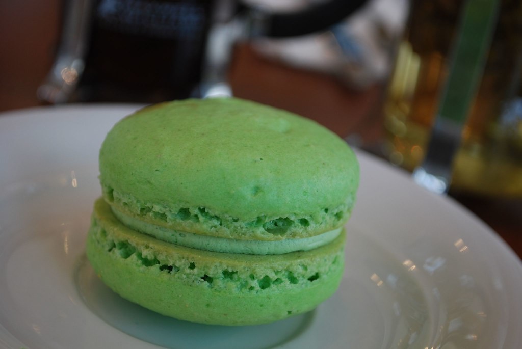 Single green macaron with a creamy filling on a white plate