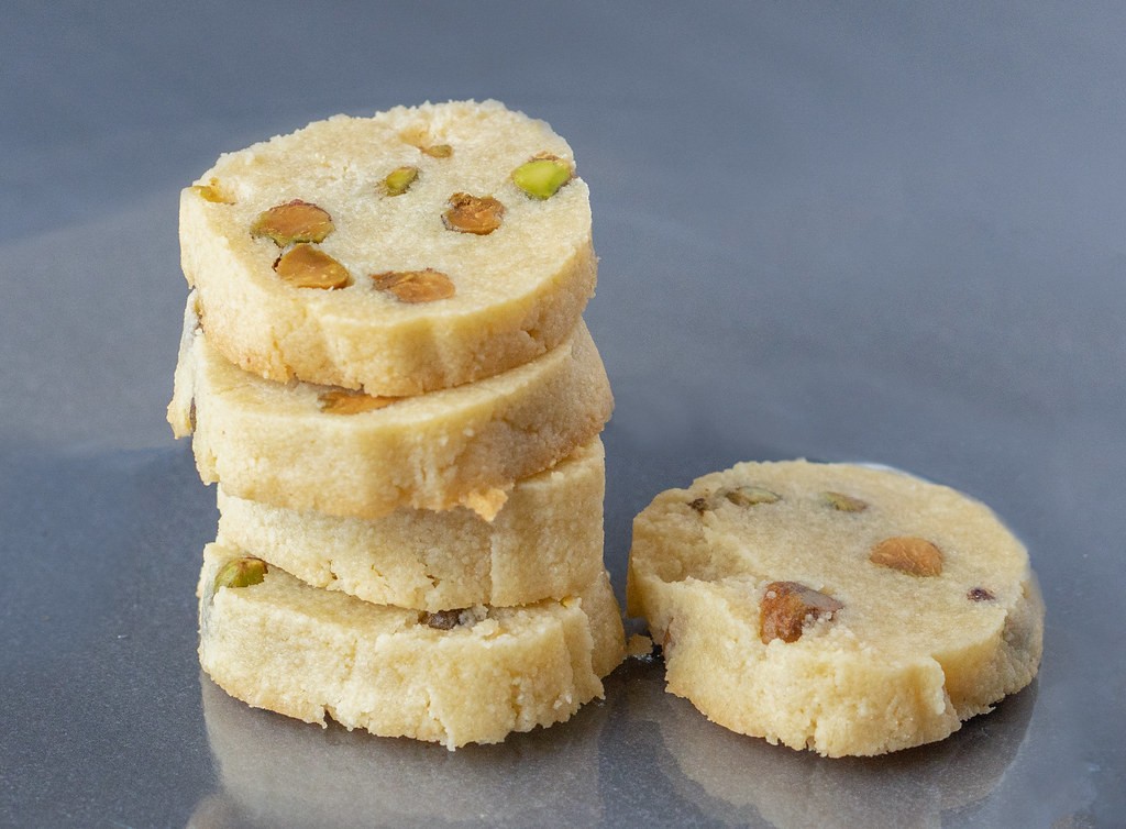 Stack of round shortbread cookies dotted with green nut pieces