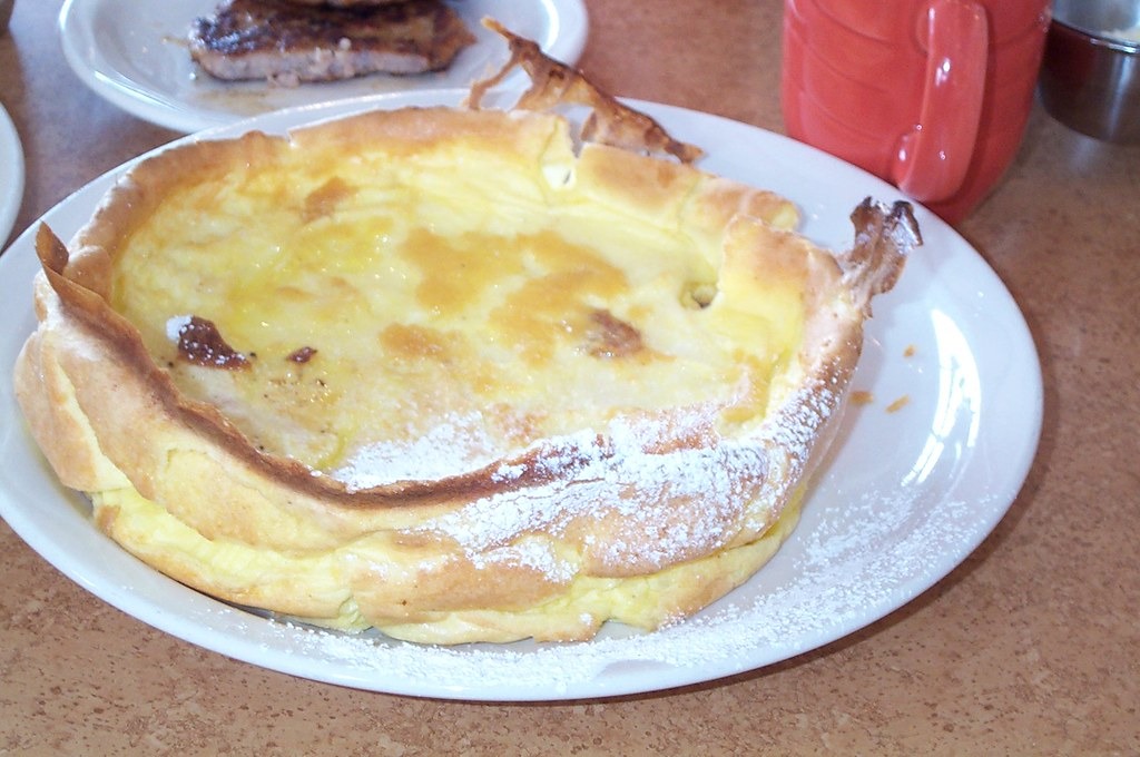 Puffed golden Dutch baby pancake dusted with powdered sugar on a plate