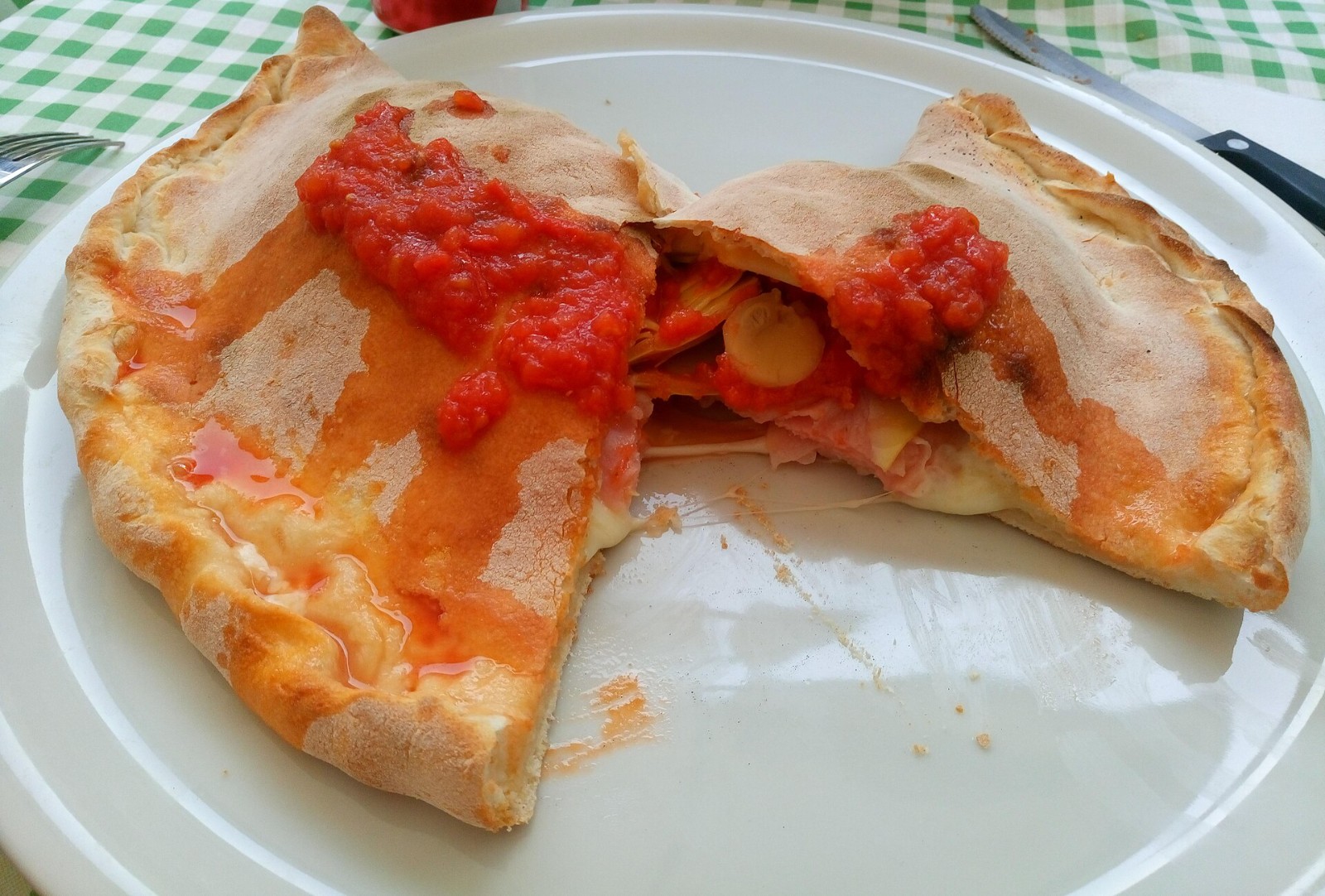 Italian calzone topped with tomato sauce on a white plate