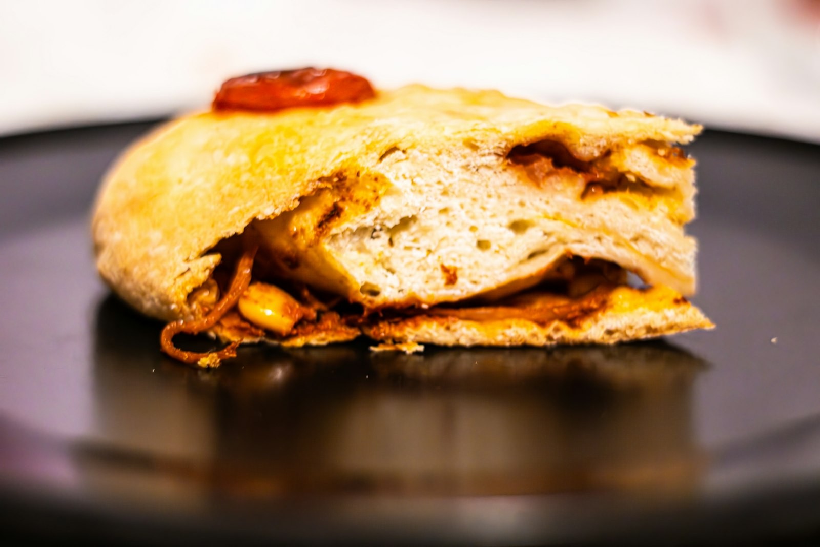 Calzone cut in half showing sausage, pepperoni and melted cheese