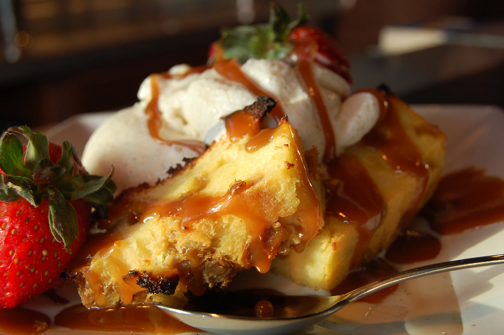 Bread pudding squares with warm sauce, whipped cream and strawberries