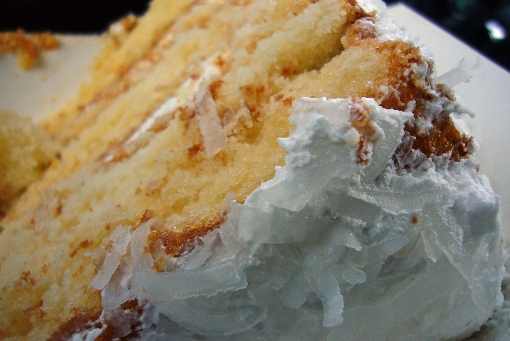 Slice of tall Southern coconut layer cake with fluffy white frosting and coconut