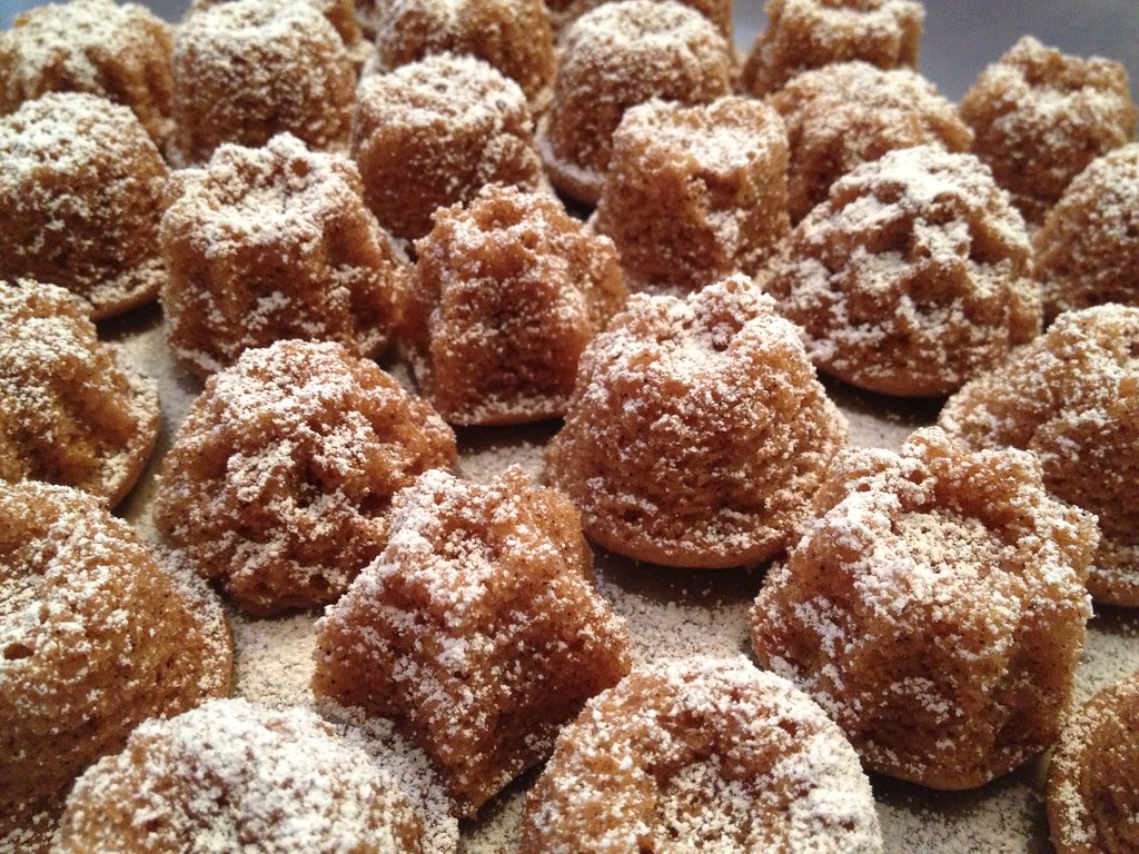 Rows of mini Bundt cakes dusted with powdered sugar on a baking tray