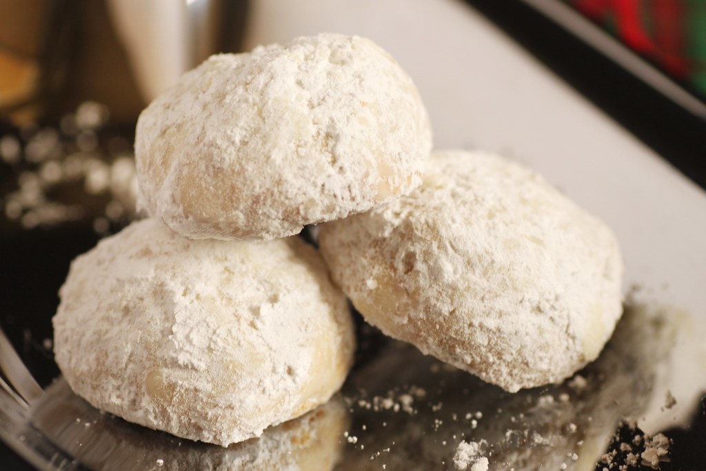 Lemon snowball cookies dusted in powdered sugar on a dark plate