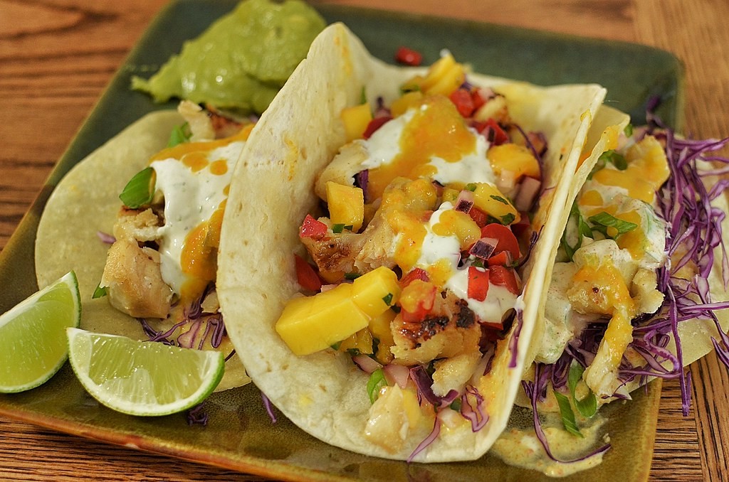 Fish tacos with mango salsa, purple cabbage and lime wedges