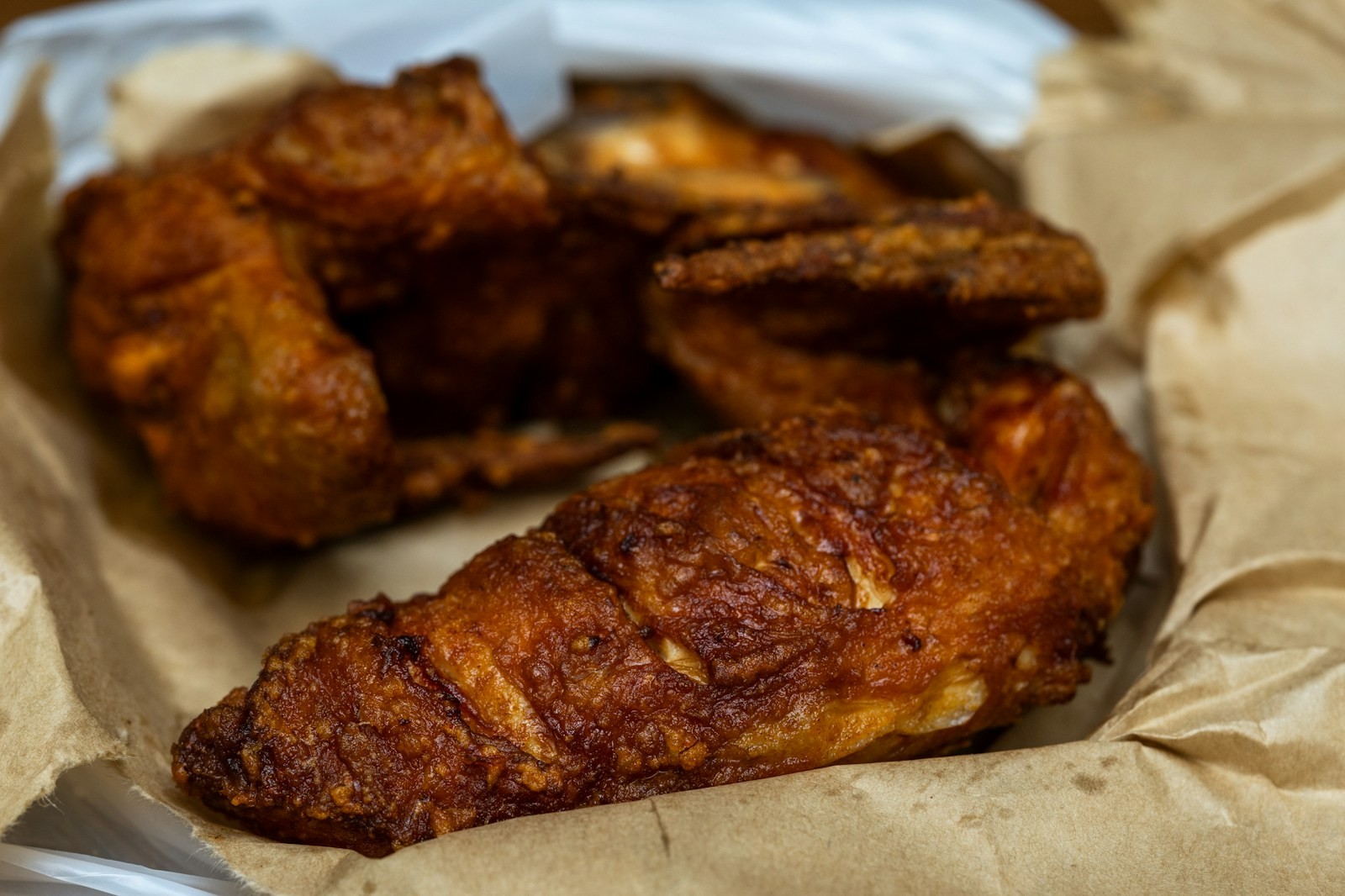 Hot honey fried chicken pieces on parchment paper